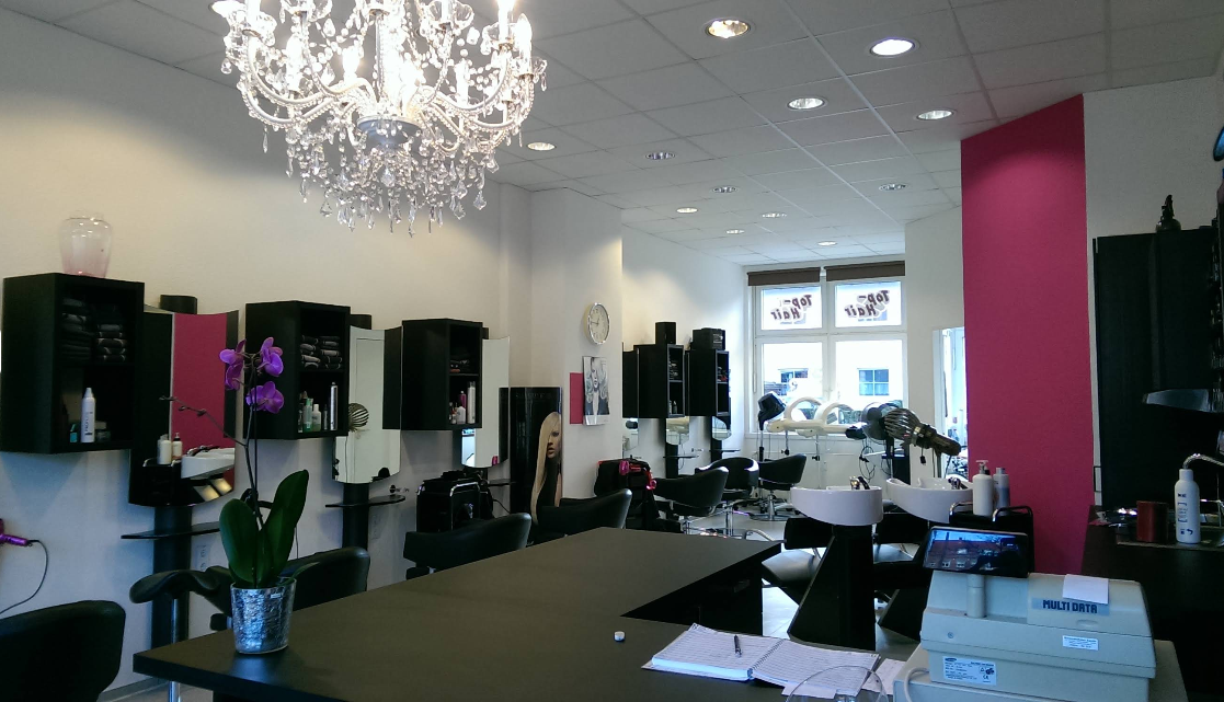 Innenansicht des Friseursalons Top Hair Inka Schwarzer in Laatzen-Rethen mit Kronleuchter und magentafarbener Wand